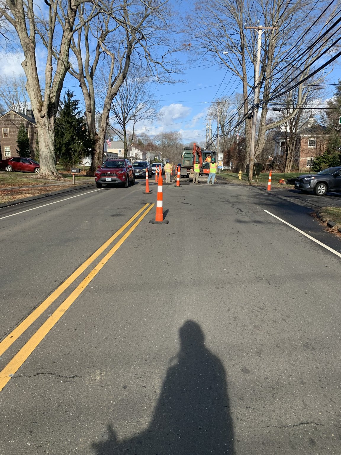 High-visibility crew members and channelizing devices at a daytime roadway work zone