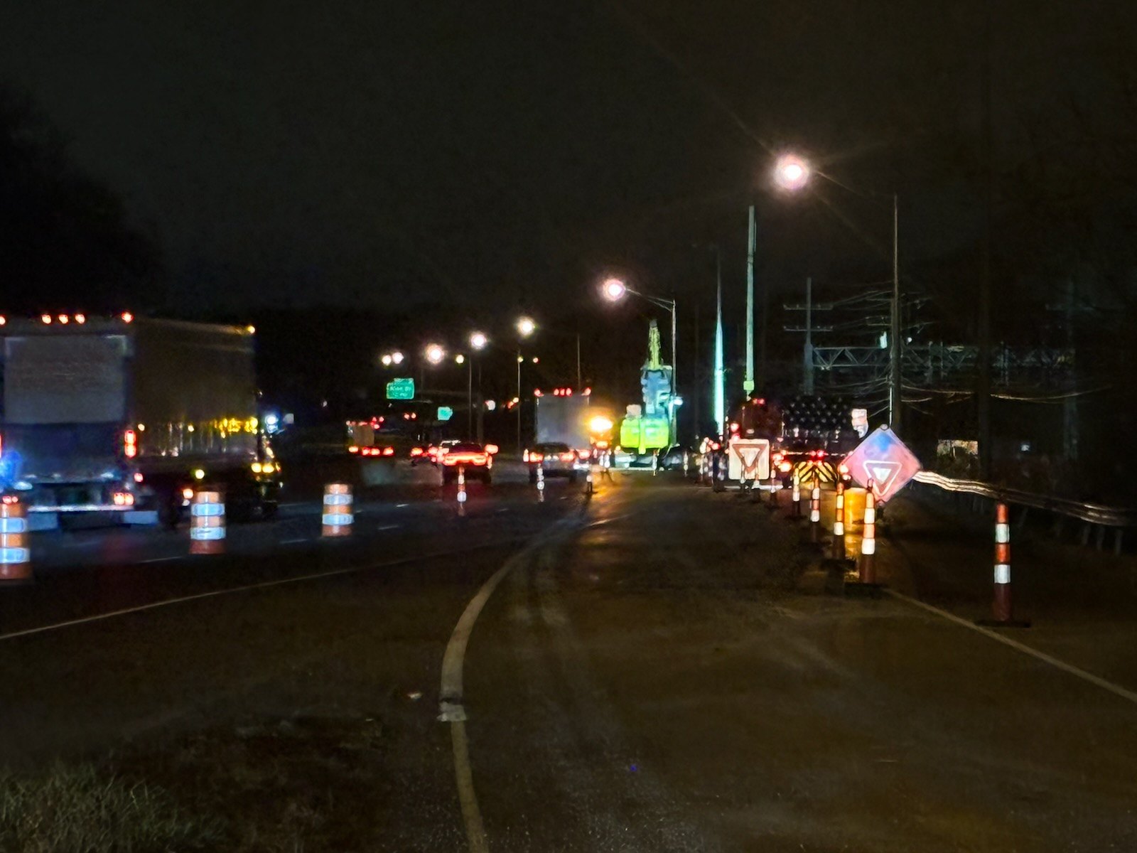 Traffic drums and construction vehicles at a nighttime roadway work zone