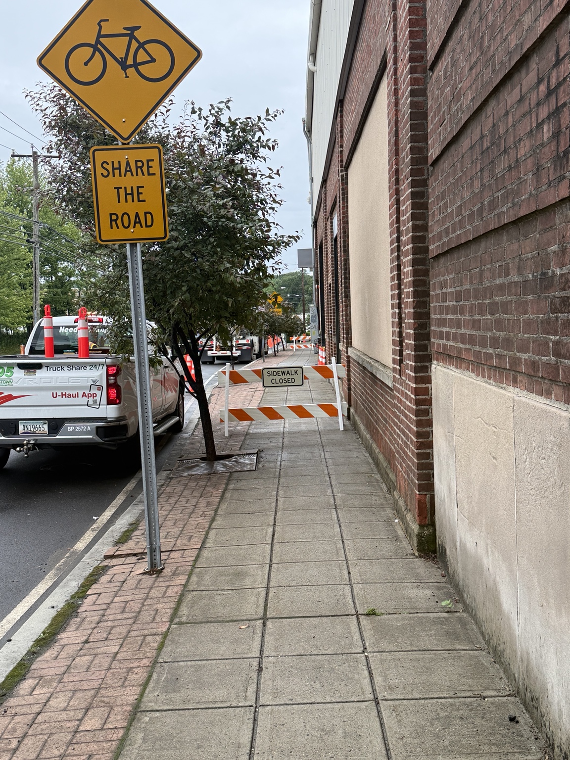 Sidewalk closed barricade alongside an active street.